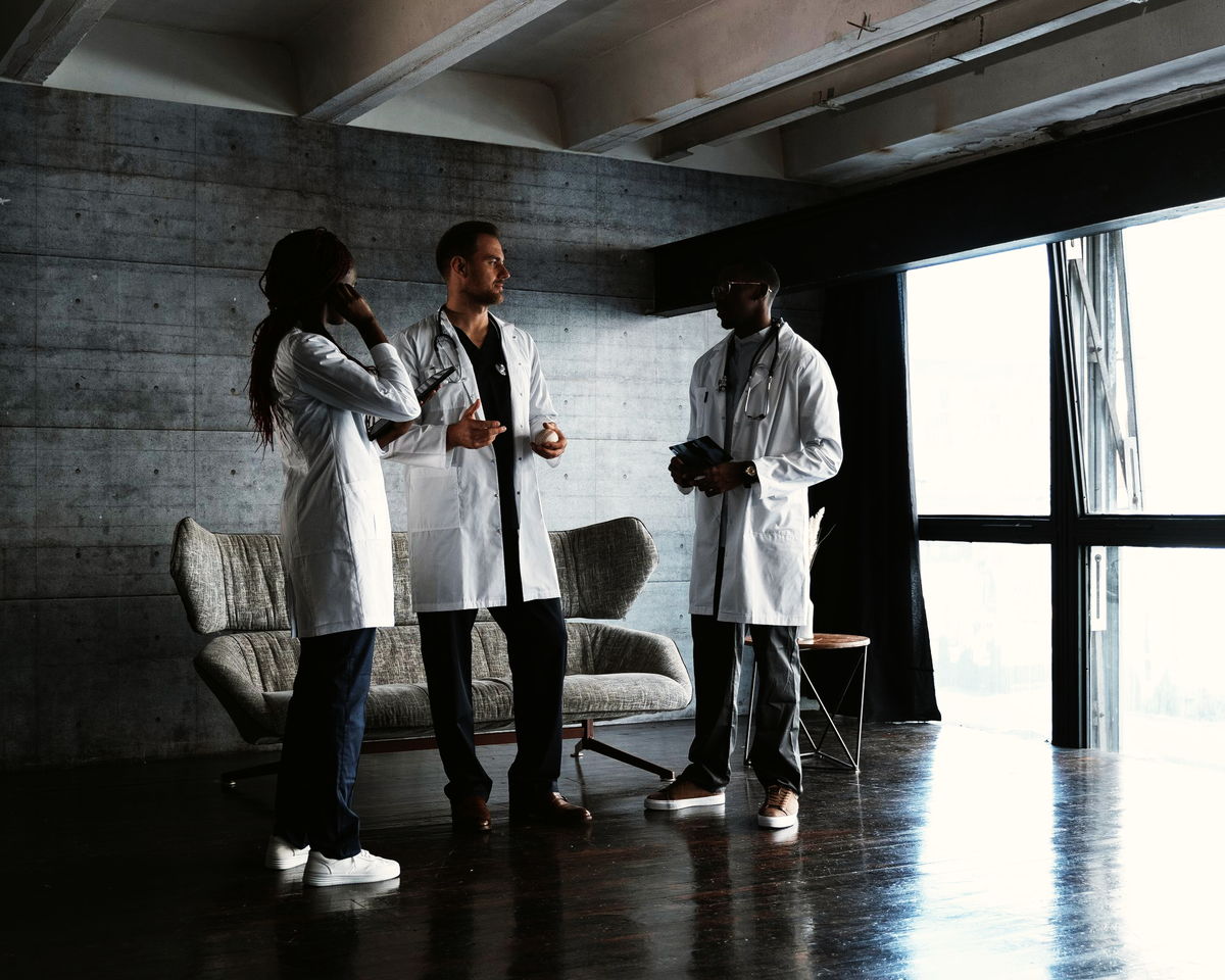 Three doctors in conversation in a bright room